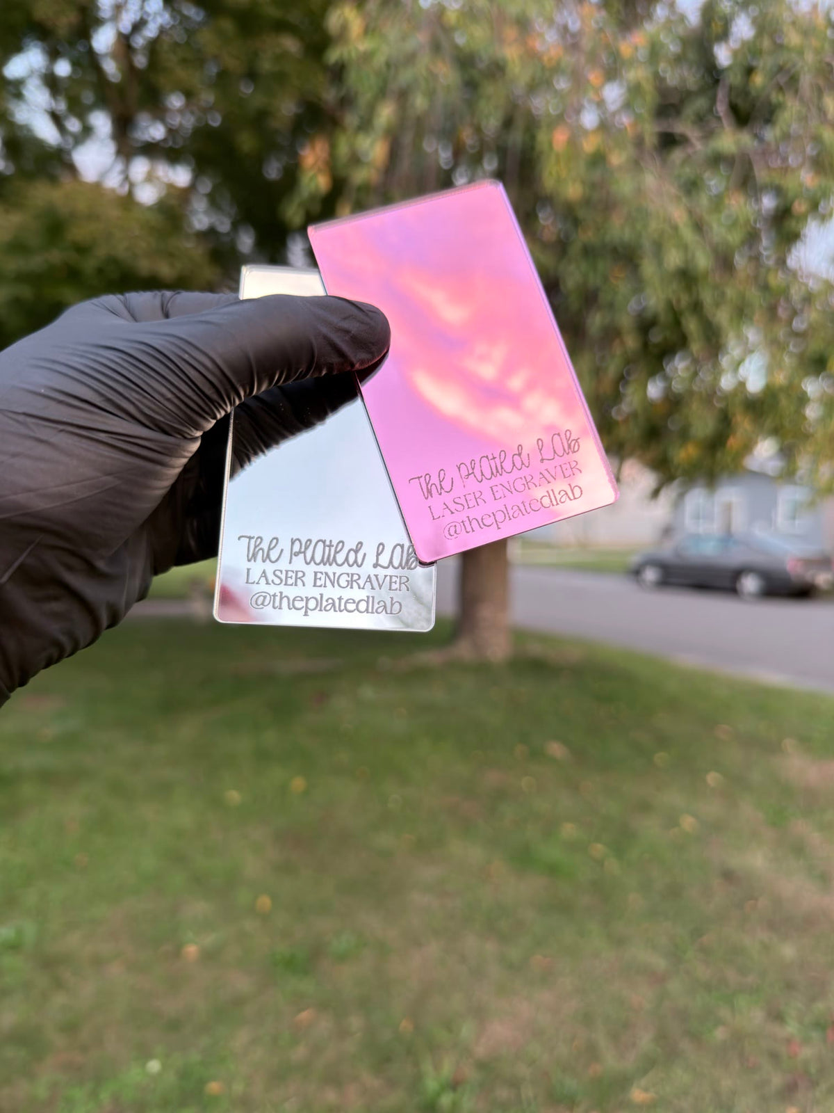 Pink, silver, gold, and hot pink mirror business cards fanned out in a gloved hand